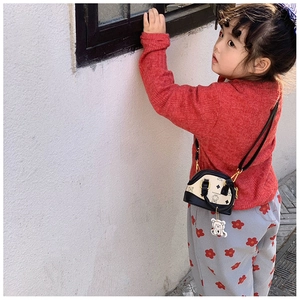 Close-up of children's shell-shaped bag featuring cute bear print and leather shoulder strap