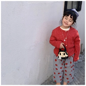 Detail of red knit cardigan and flower print wide-leg trousers for kids in a stylish set