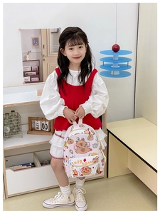Girl holding cream backpack with all-over capybara cartoon print and red accents