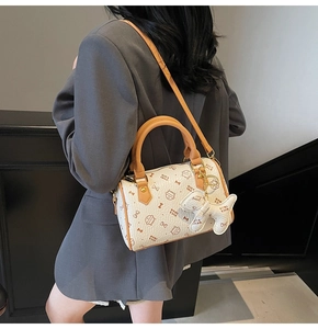 Model wearing a cream-colored Boston bag with cat print and bone charm accessory