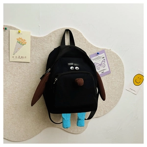 Dettaglio zaino cane nero con orecchie 3D e gambe blu su pannello decorativo carino