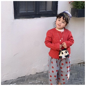 Detail of red waffle knit cardigan and floral trousers with mini teddy bear handbag