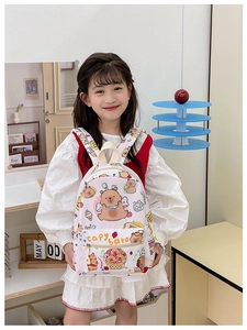 Pink cartoon Capybara schoolbag worn by child model in a cozy indoor setting