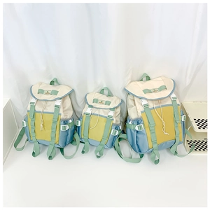 Three sizes of color-block nylon backpacks with buckles and side pockets on a white shelf