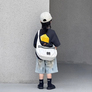 Vue arrière d'un enfant portant un sac bandoulière en toile blanche avec numéro 88