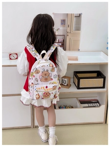 Detail view of pink plaid kids backpack featuring cute capybara and dessert cartoon prints
