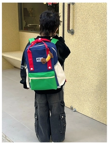 Détail du sac à dos enfant tricolore avec poche latérale et petit pendentif chien