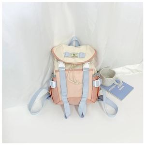 Detail of color-block nylon backpack featuring drawstring closure and buckle straps