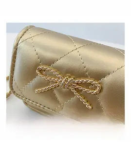 Close-up of golden quilted PU leather mini bag with decorative metal bow clasp detail