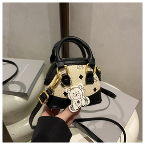 Detail of mini shell bag with bear print, lychee leather texture and gold hardware