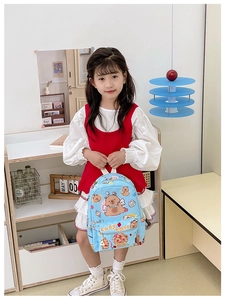 Close-up of light blue plaid backpack with cartoon capybara prints and white zipper pocket