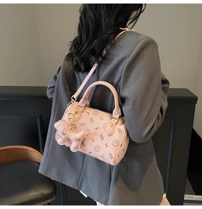 Detail of pink Boston bag with cat prints, golden hardware and matching animal charm