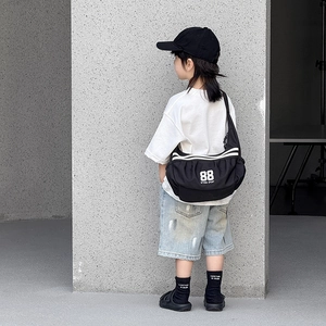 Détail du sac bandoulière noir enfant avec rayures blanches et logo sportif imprimé 88
