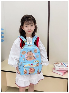 Detailed view of the cute Capybara cartoon backpack worn by a young girl in white dress