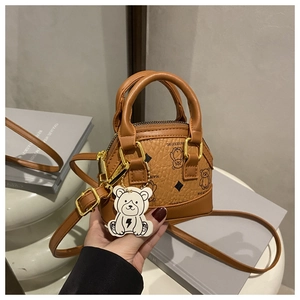 Detail of a mini brown shell bag with cute bear prints and a white lightning bear charm