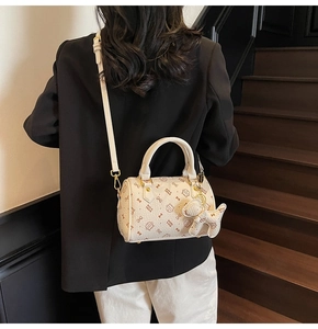 Detail of Boston bag with cat print, white top handles and small puppy charm attachment
