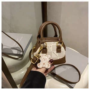 Close-up of mini PU leather handbag with bear print and cute hanging teddy bear charm