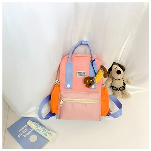 Détail du sac à dos enfant bicolore avec un pendentif en peluche teckel et poche frontale
