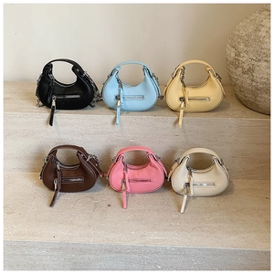 Collection of six colorful mini crescent handbags with litchi grain texture on stone steps