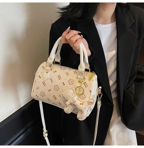 Detail of white Boston bag with cat prints, crossbody strap and a kitten charm hanging