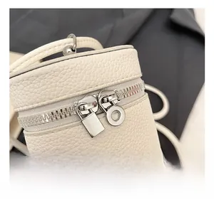 Detailed macro view of cream litchi grain leather bag with dual silver zippers and lock