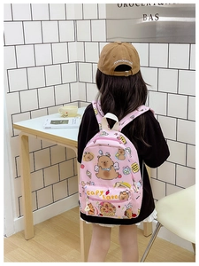 Pink checkered Capybara backpack for school kids shown on model in cozy room setting