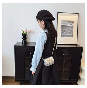 Detail of silver quilted mini crossbody bag with golden bow on a child model
