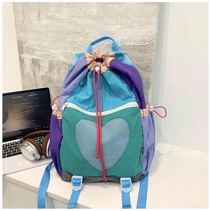 Detail of color-block drawstring backpack with heart mesh window on a white table