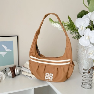 Détail du sac bandoulière en nylon caramel avec broderie 88 et rayures sportives