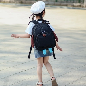 Zaino per bambini a forma di cane nero con orecchie 3D indossato in un parco