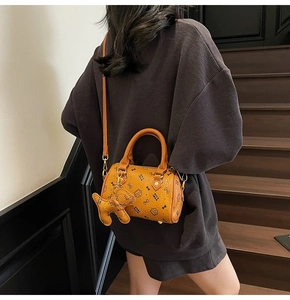 Detail of orange-brown boston bag with cute cat prints and a dog-shaped leather charm