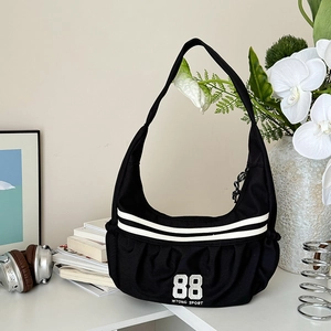 Vue détaillée du sac bandoulière de sport noir avec rayures blanches et design plissé