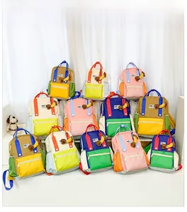 Détail de sacs à dos enfants multicolores avec logo NIE et pendentifs ours en peluche