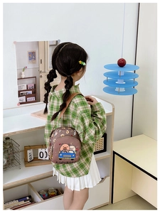 Detail of a brown kids crossbody bag featuring a cute cartoon capybara driving a blue car