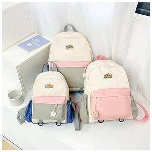 Three sizes of color-block school backpacks for kids in a minimalist set display