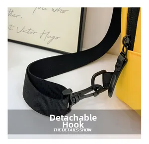 Detail view of a bright yellow kids crossbody bag featuring a black detachable swivel hook