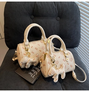 Detail of two white cat print Boston bags with litchi grain texture and charms