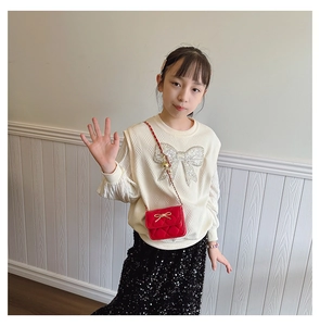 Detail of red quilted crossbody bag for girls with gold bow and chain strap
