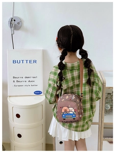 Detail showing an adjustable brown strap and cartoon capybara print on a child's bag