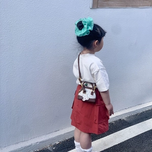 Kids mini crossbody bag with cute bear print and charm, shown on a child model outdoors