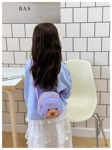 Detail of cute purple kids crossbody bag featuring cartoon capybara print and strap