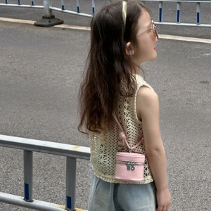 Detail of pink cylindrical mini bucket bag paired with a crochet vest for kids