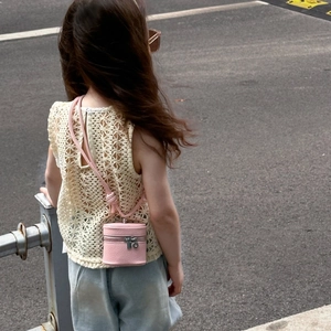 Lifestyle shot of a little girl wearing a pink cylindrical mini leather bucket bag
