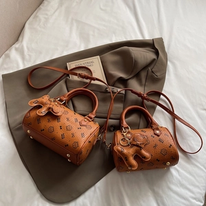 Close-up of brown Boston bags featuring cute cat prints with adjustable shoulder straps