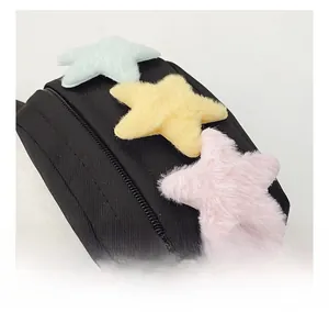 Détail du sac en toile noire avec des étoiles en peluche colorées et une fermeture éclair