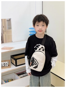 Detail of beige kids chest bag with black geometric logo and branded nylon strap
