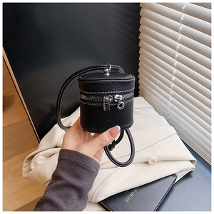 Close-up of black lychee grain leather mini bucket bag with white contrast stitching