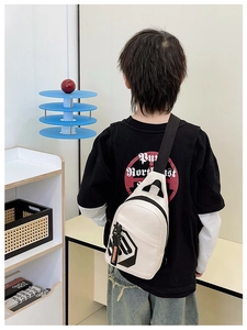 Rear view of a child wearing a white leather chest bag with black adjustable strap and charms