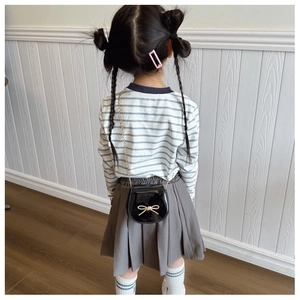 Vista posteriore di una bambina con borsa a tracolla in pelle verniciata nera e fiocco d'oro