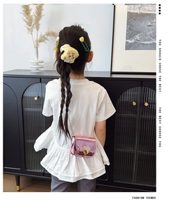 Detail of pink metallic crossbody bag with heart clasp and cute bear hair accessories